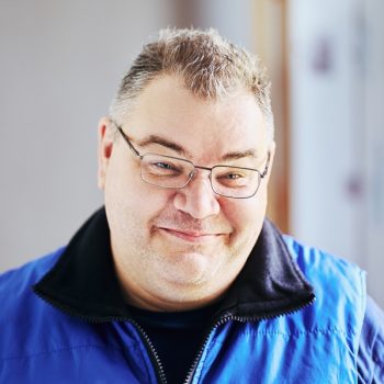 Good natured face of chubby Caucasian man in her 40s wearing glasses.