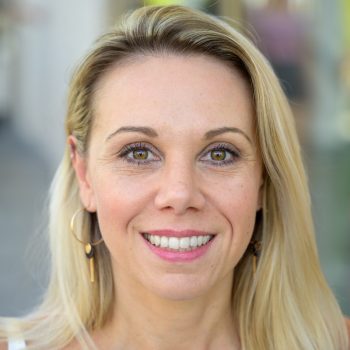 Close up face portrait of a vivacious blond woman looking at the camera with a beaming happy smile