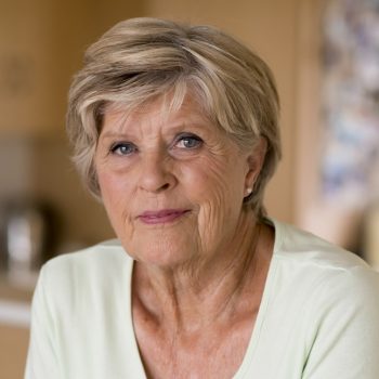 beautiful portrait of pretty and sweet senior mature woman in middle age around 70 years old smiling happy and friendly at home kitchen in aging and lifestyle concept